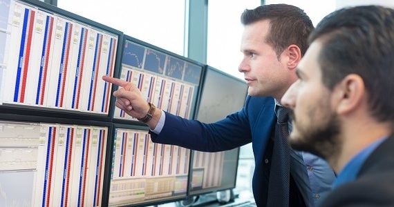 two professionals looking at data charts on large computer screens